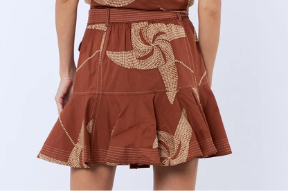 Woman wearing a brown dress with floral patterns on a white background