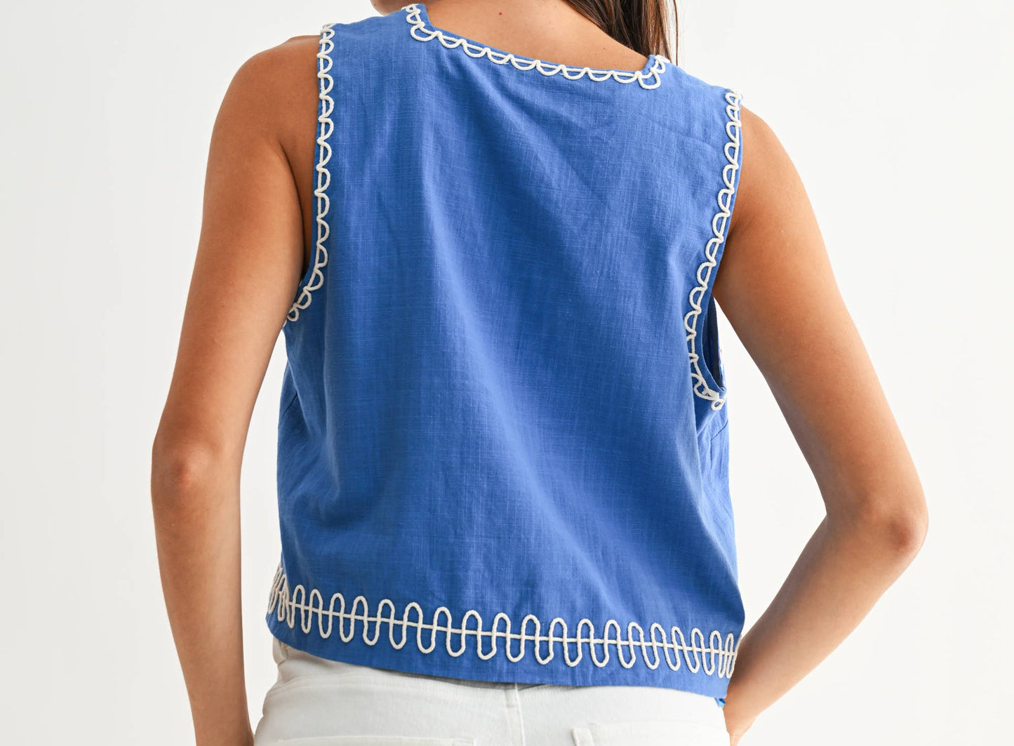 Woman wearing a blue sleeveless top with white trim on a white background