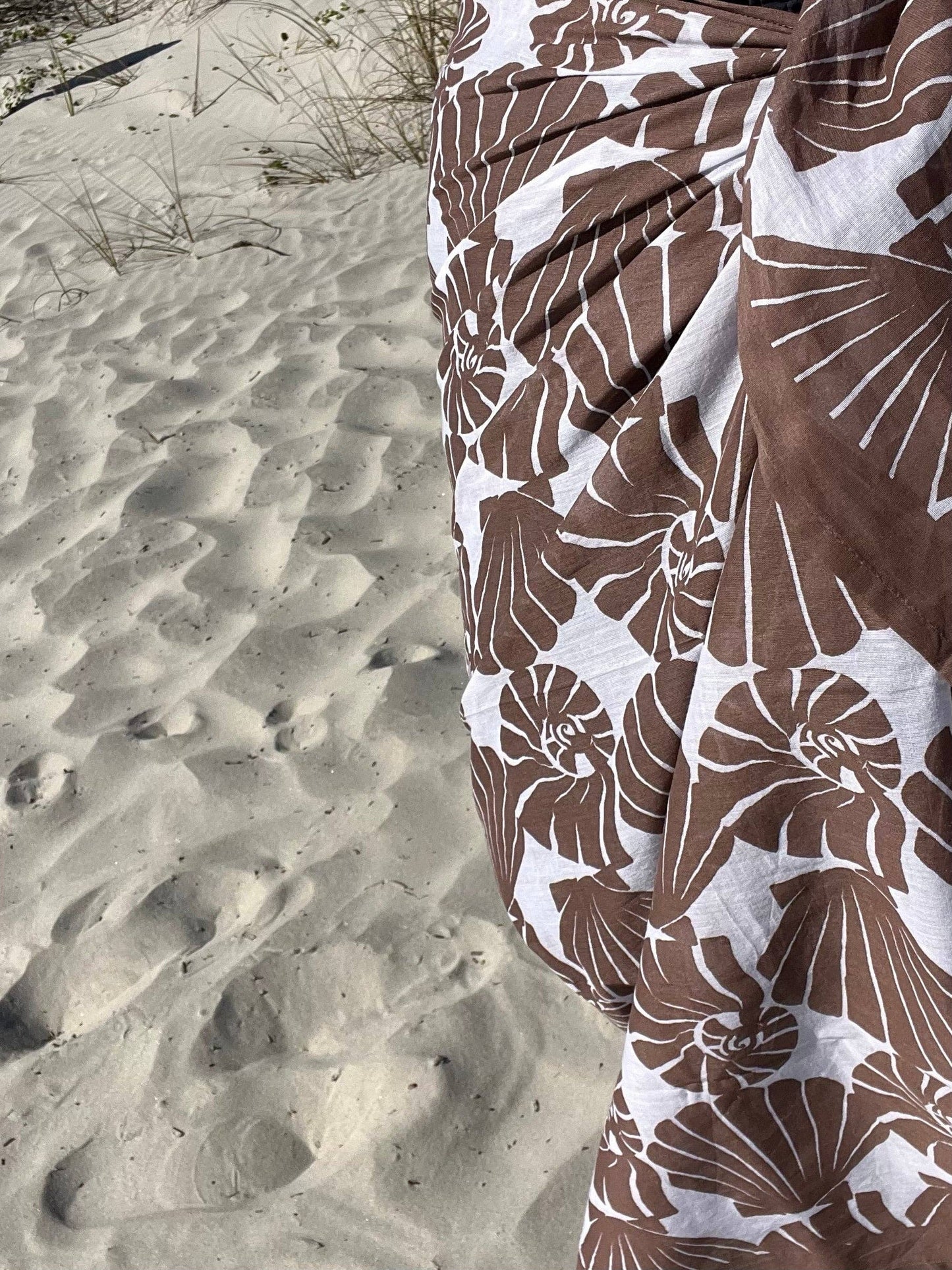 Brown and white floral patterned fabric on a sandy background