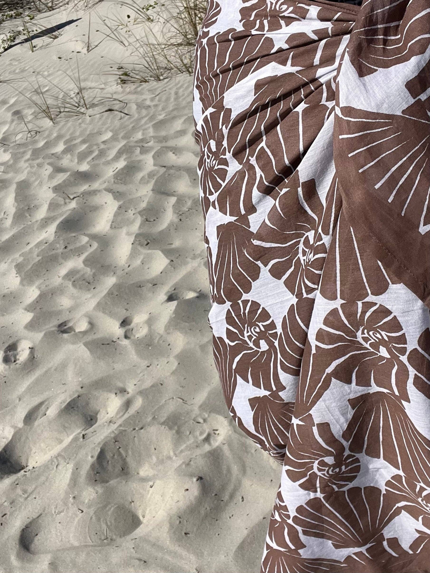 Brown and white floral patterned fabric on a sandy background