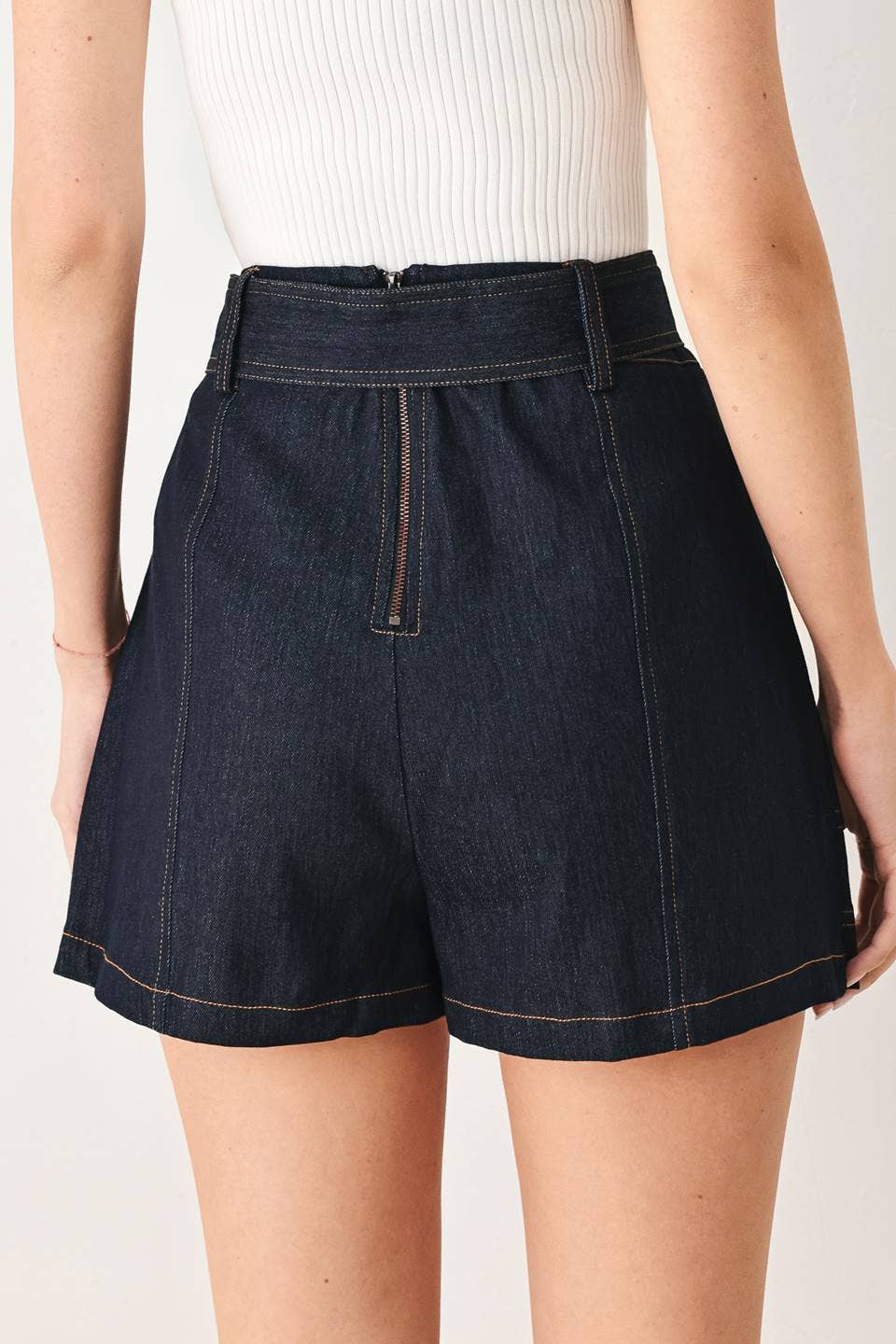 Dark denim shorts worn by a person on a plain background
