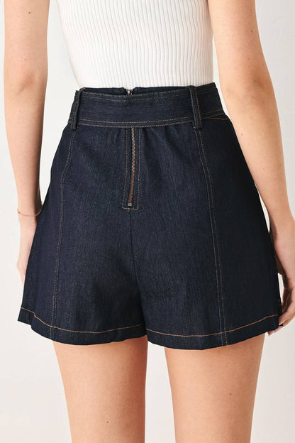 Dark denim shorts worn by a person on a plain background