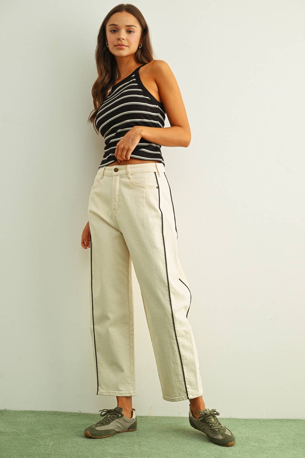 Woman wearing a black and white striped top and beige pants with a white background