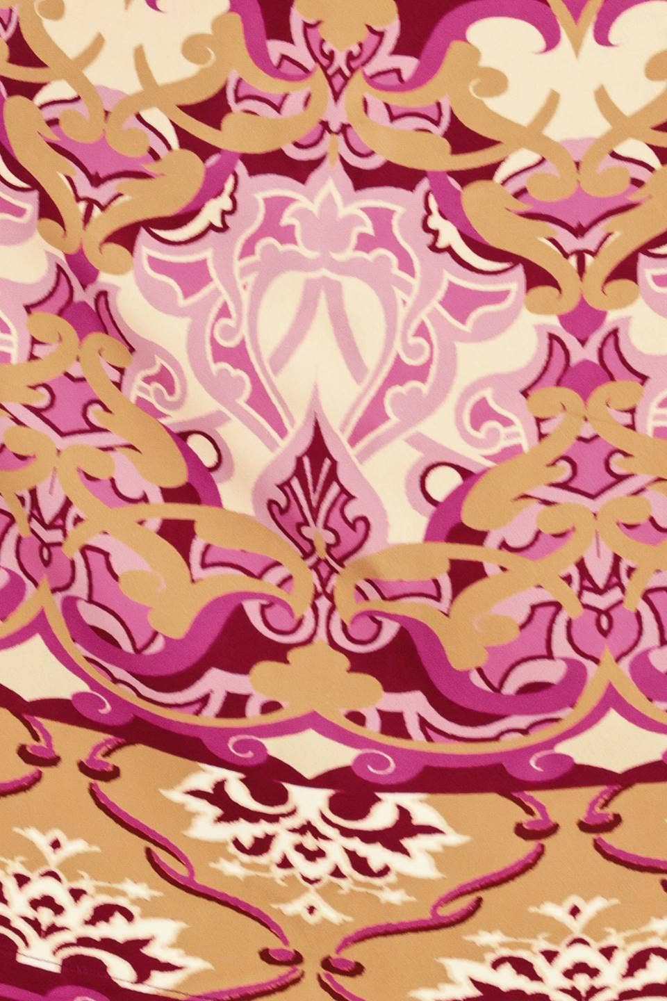 A close-up of an ornate damask pattern with swirling scrollwork in pink, magenta, beige, and cream tones.