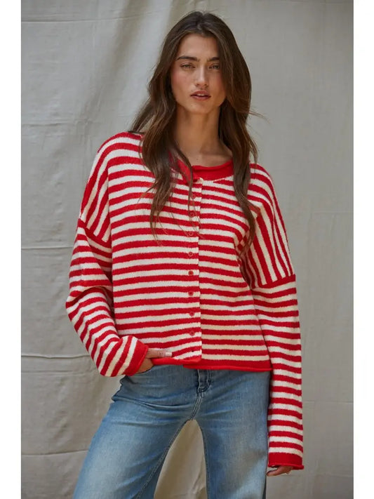 Woman wearing a red and white striped sweater and blue jeans against a plain background
