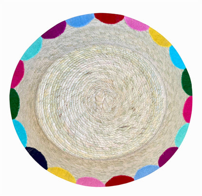 Round woven mat with colorful polka dot border on a white background
