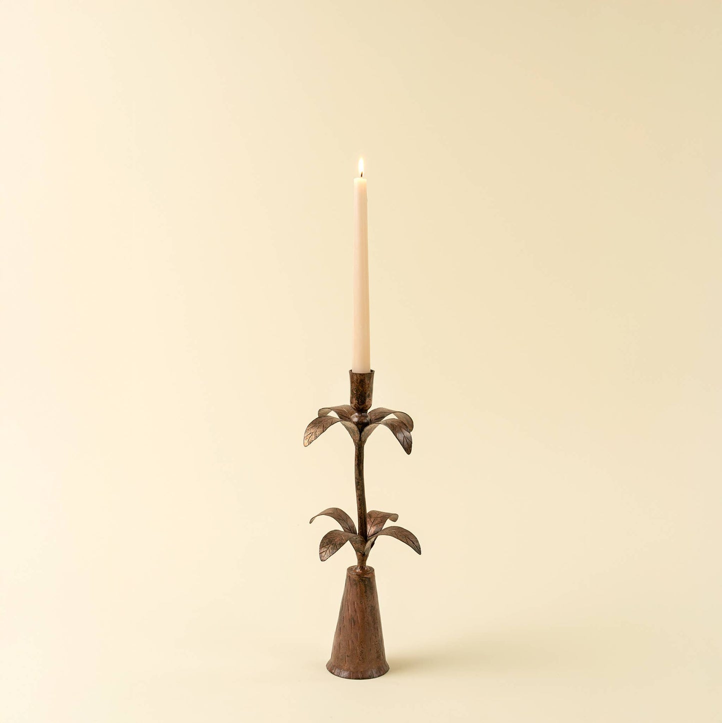 Decorative candle holder with a lit candle on a beige background