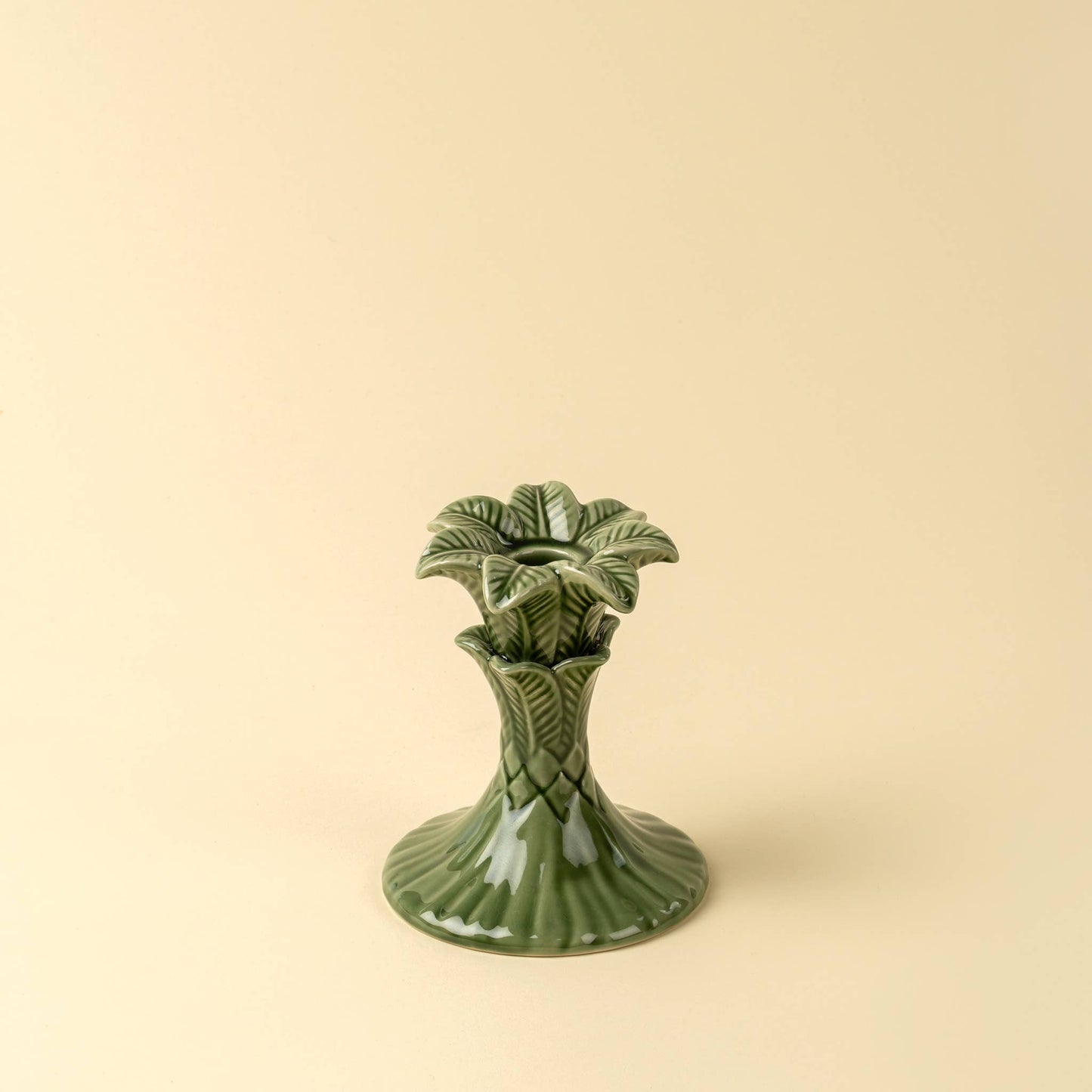 Green ceramic vase with leaf design on a beige background
