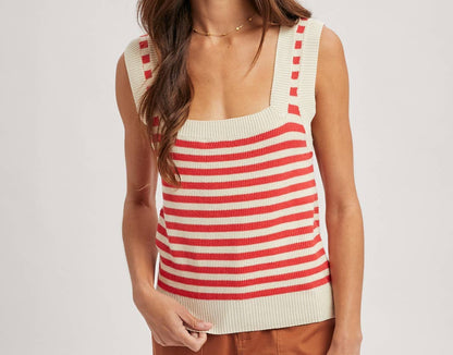 Woman wearing a red and white striped sleeveless top with brown pants on a plain background