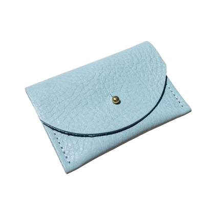 Light blue leather cardholder with a gold button on a beige background