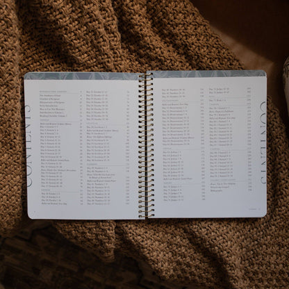 Open spiral-bound notebook with a table of contents on a textured brown surface
