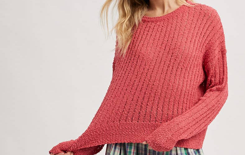Woman wearing a pink sweater and plaid pants on a white background