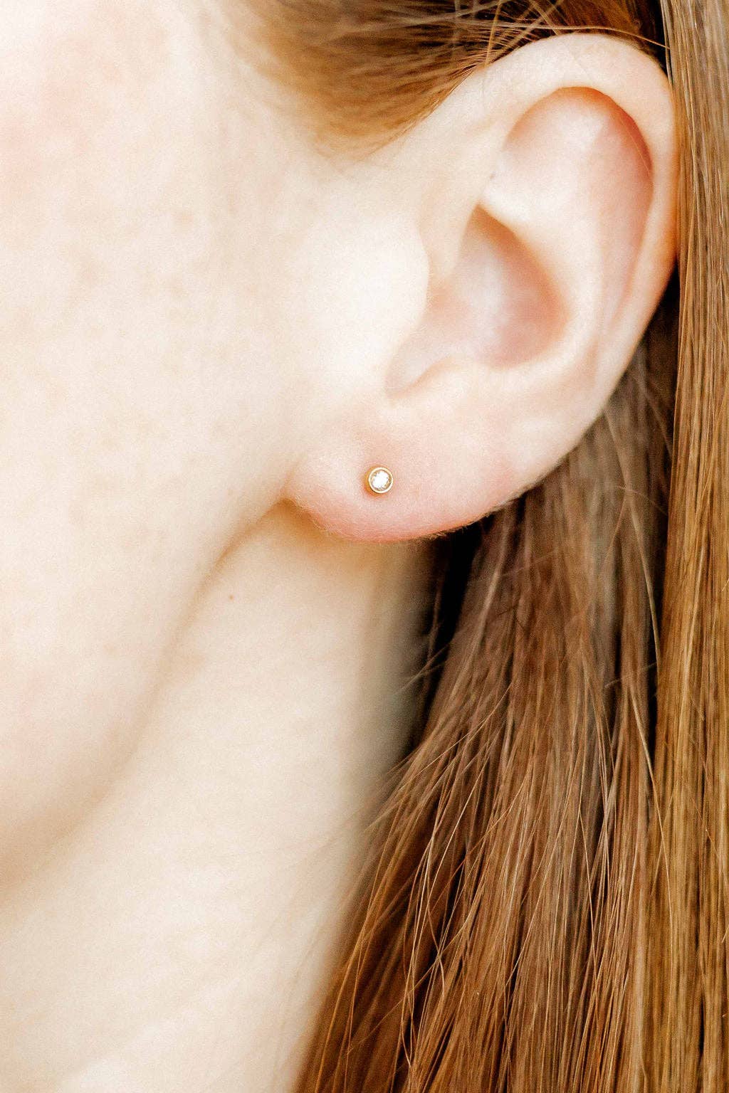 Close-up of an ear with a gold stud earring