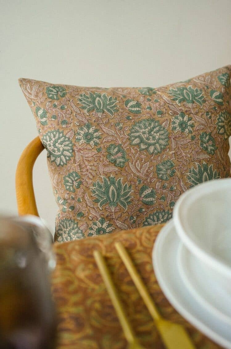 Patterned pillow on a table with white plates and gold cutlery