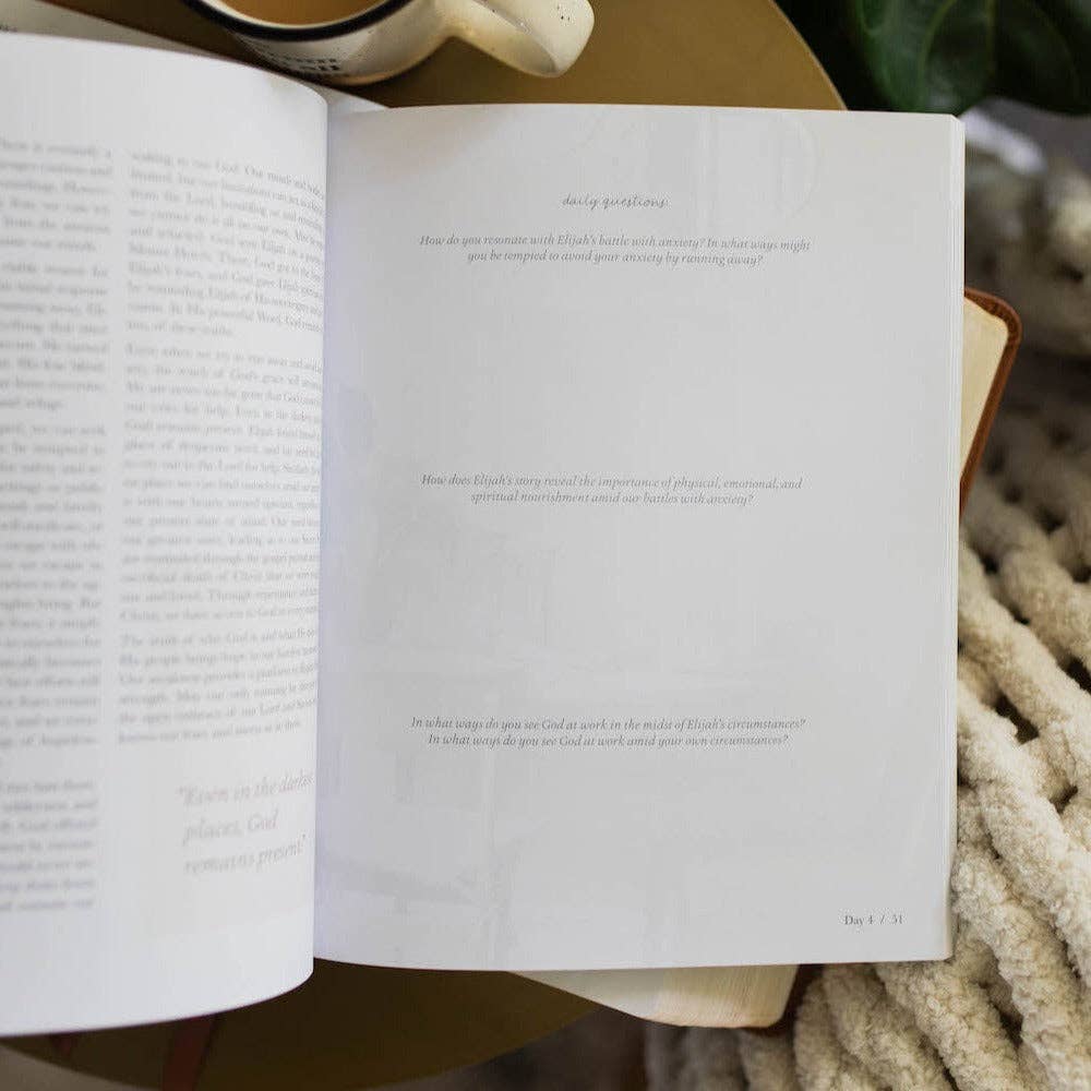 Open book with text on a wooden surface, surrounded by cozy items.