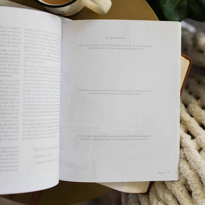 Open book with text on a wooden surface, surrounded by cozy items.