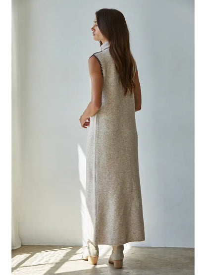 Woman wearing a long beige dress in a bright room