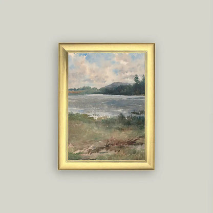 Framed painting of a landscape with water and sky on a gray wall