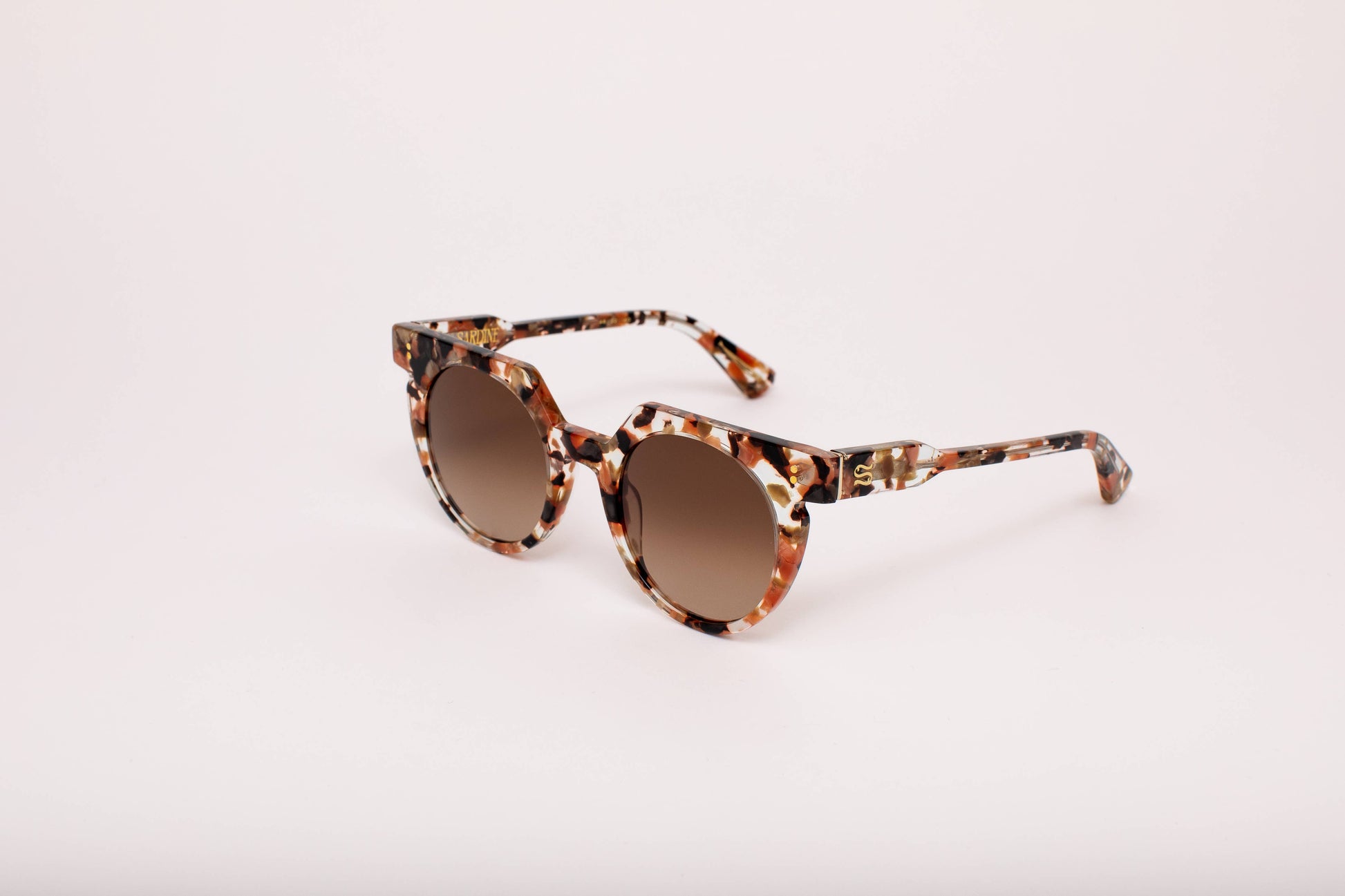 Sunglasses with tortoiseshell frame and brown lenses on a light pink background