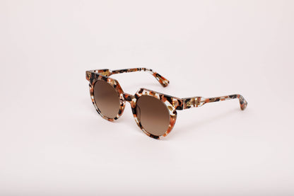 Sunglasses with tortoiseshell frame and brown lenses on a light pink background