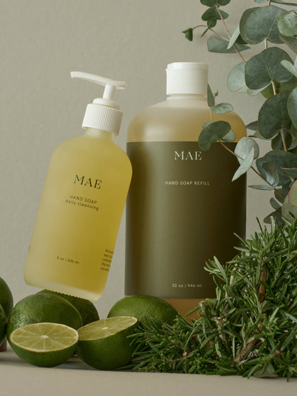 Two hand soap bottles labeled 'MAE' with green limes and herbs on a neutral background