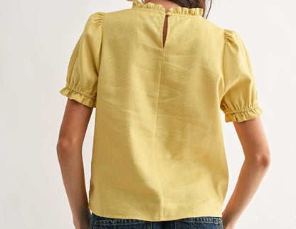 Woman wearing a yellow blouse with short sleeves and blue jeans on a white background