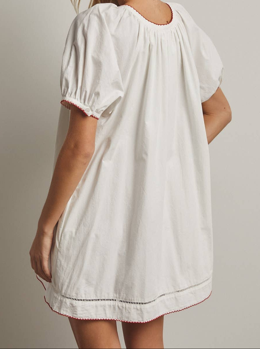Woman wearing a white dress with short sleeves against a plain background