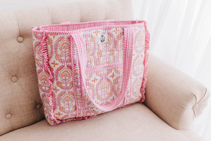 Pink and white patterned blanket draped over a beige couch