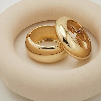 Two gold rings on a beige surface