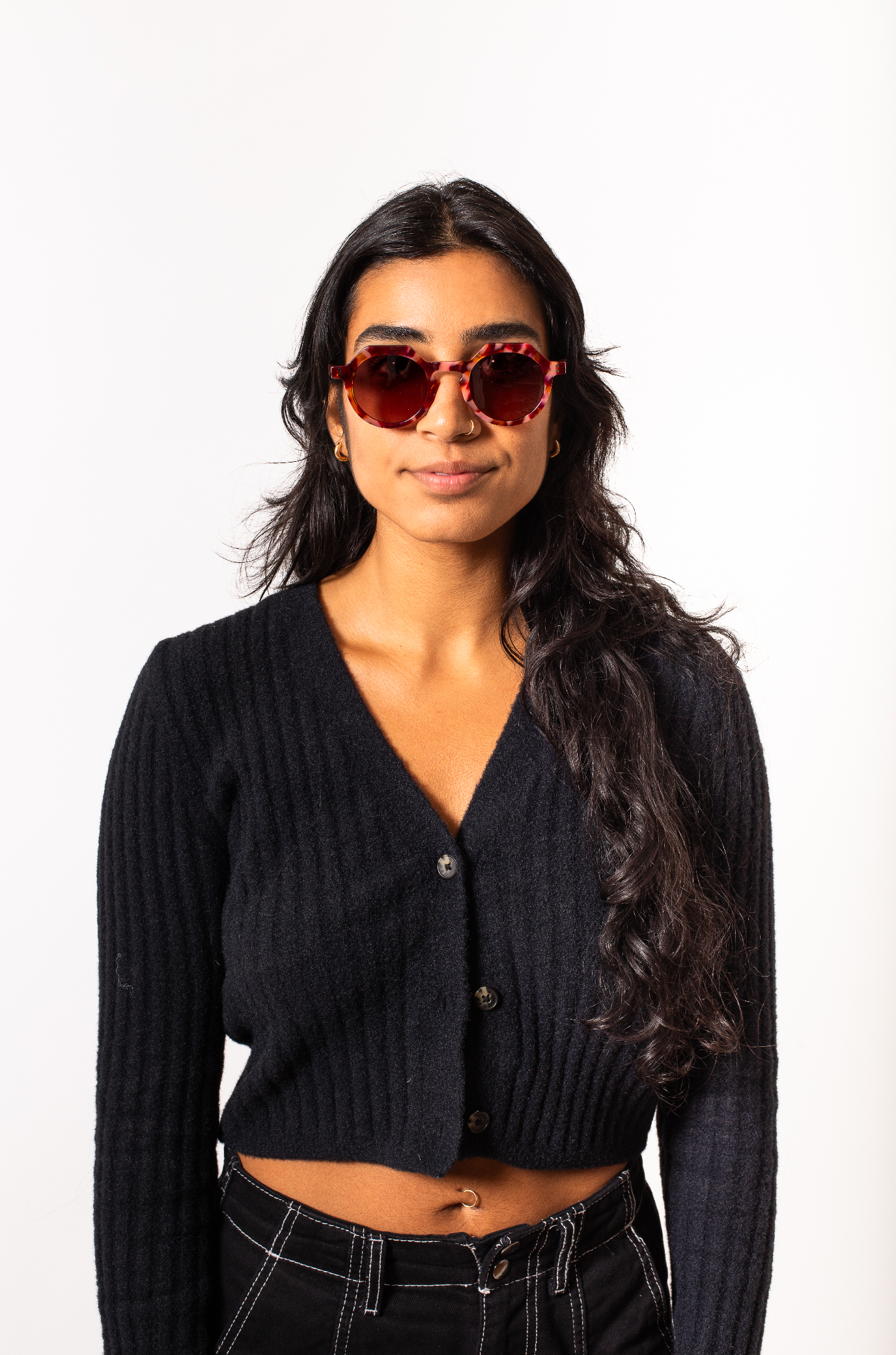Woman wearing a black cardigan and sunglasses on a white background
