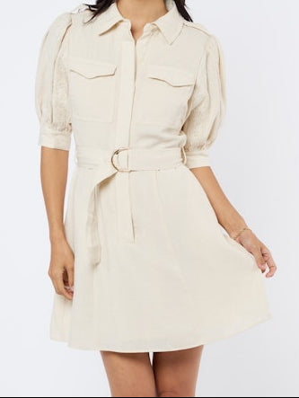 Woman wearing a cream-colored dress with a belt on a white background