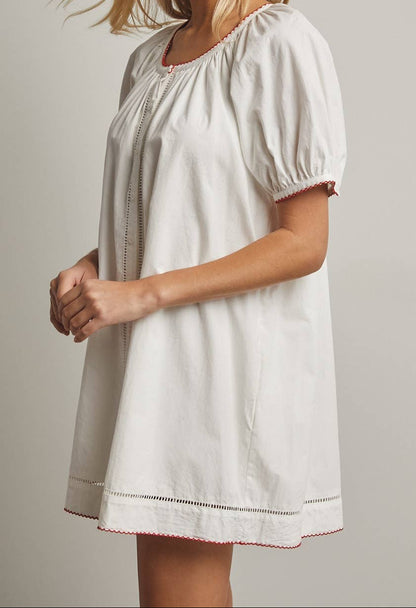 Woman wearing a white dress with short sleeves against a plain background
