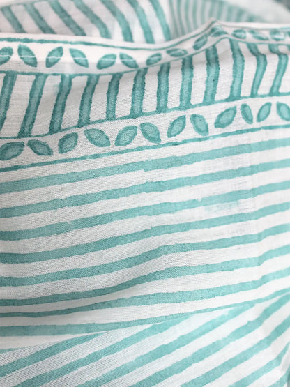 Close-up of fabric with teal stripes and leaf patterns on a white background