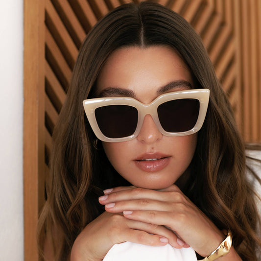 Woman wearing stylish sunglasses with a neutral background