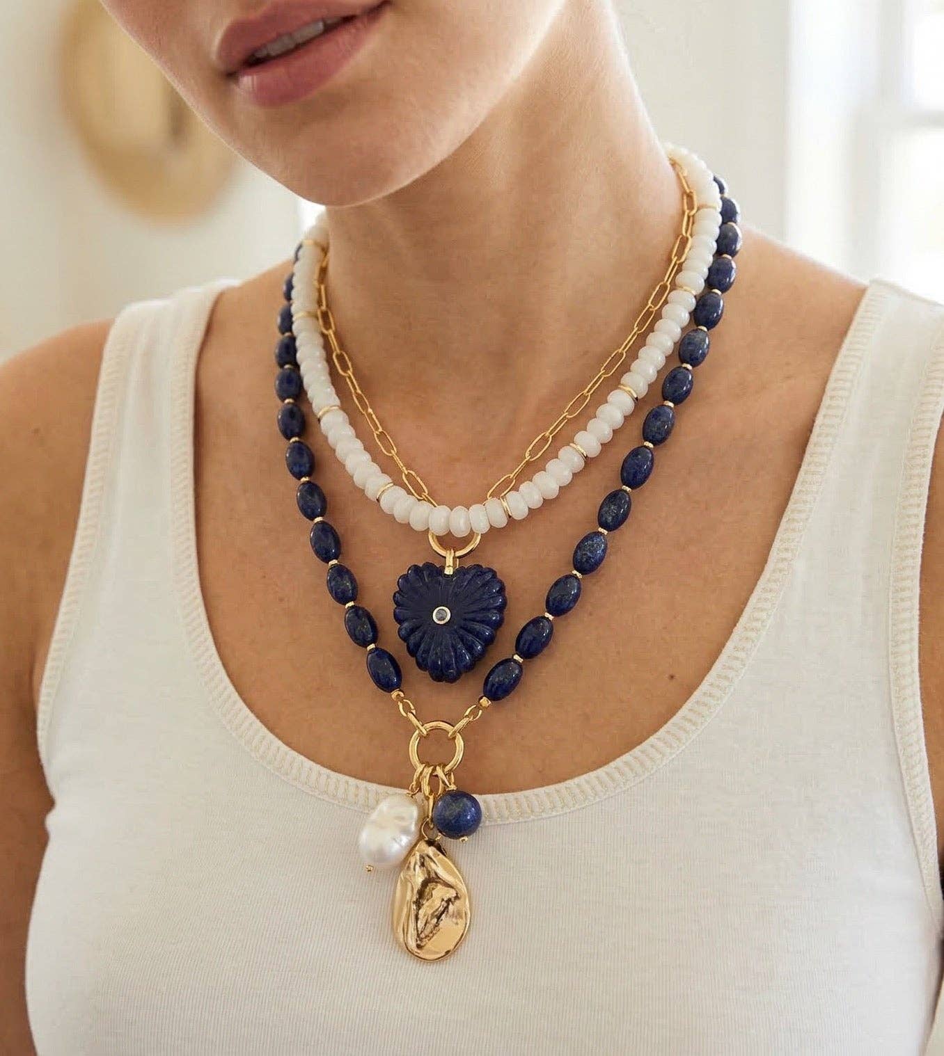 Woman wearing a necklace with blue and gold beads and pendants.