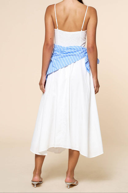 Woman wearing a white dress with a blue striped top on a beige background