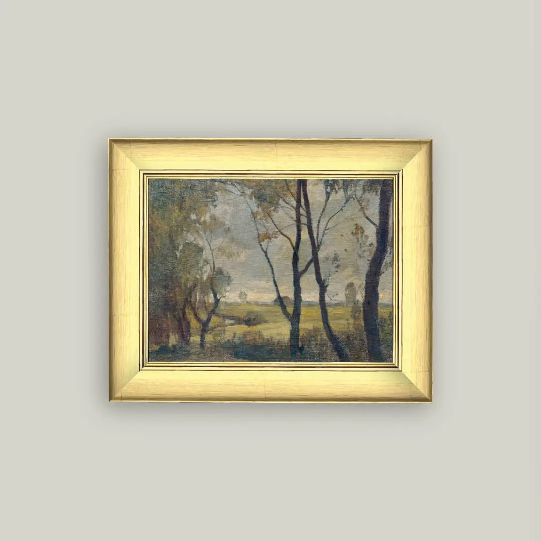 Framed painting of a landscape with trees and open field on a light gray wall.