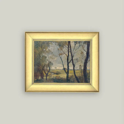 Framed painting of a landscape with trees and open field on a light gray wall.