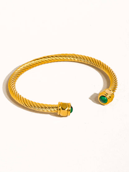 Gold bracelet with green gemstones on a white background