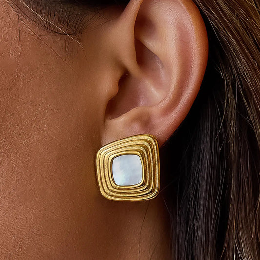 Gold earring with a central gemstone worn on an ear