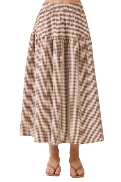A brown and beige gingham tiered midi skirt worn by a model, paired with tan flat sandals, against a plain white studio background.
