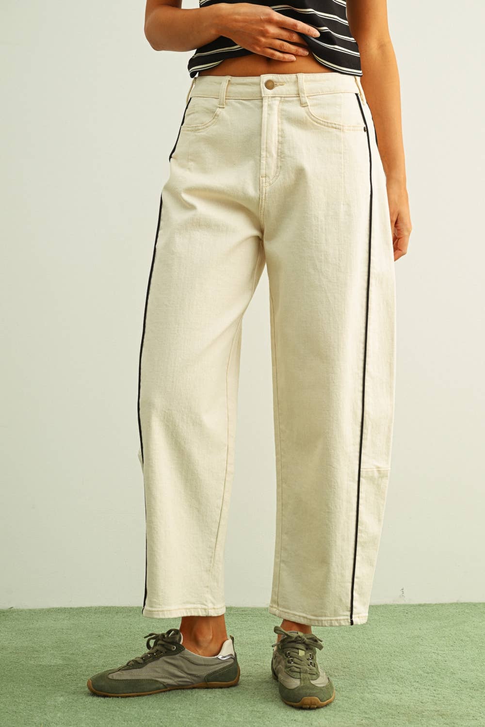 Person wearing beige pants with black stripes on a plain background