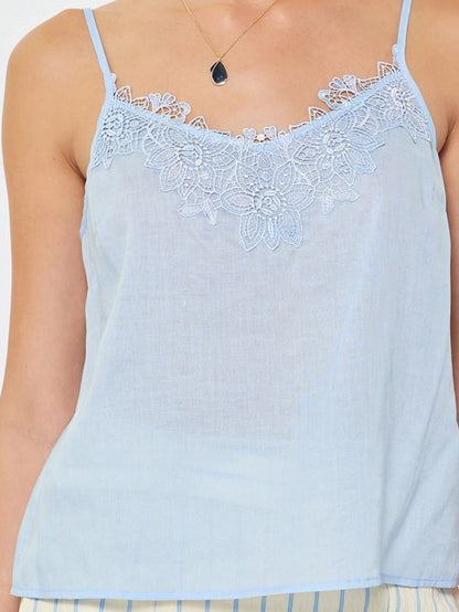 Woman wearing a light blue lace-trimmed top against a white background