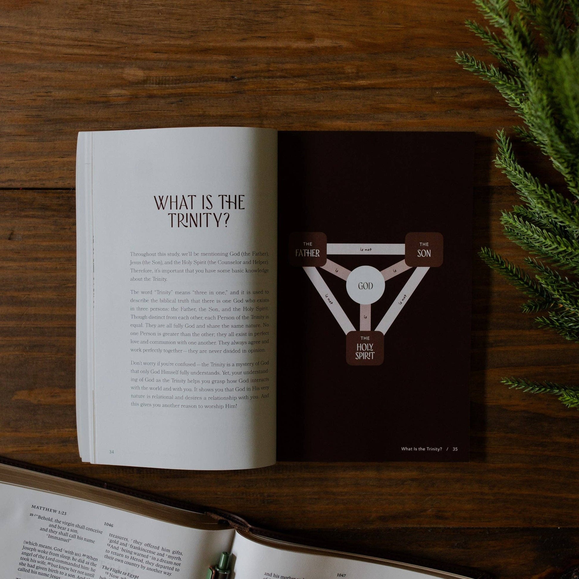 Open book on a wooden surface with a diagram of the Trinity on a dark background