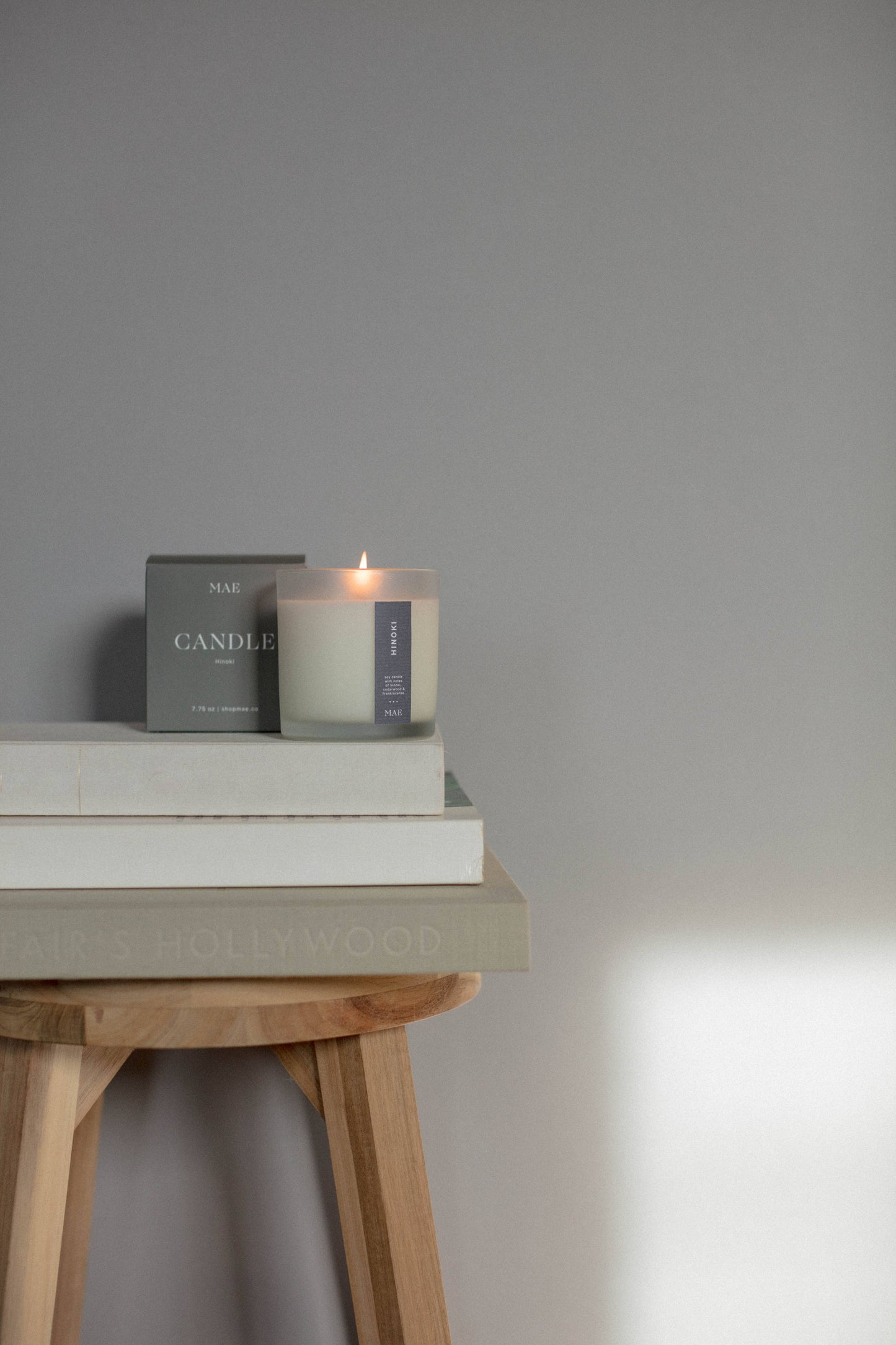 Candle and books on a wooden stool against a gray wall