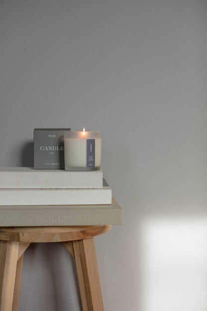 Candle and books on a wooden stool against a gray wall