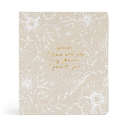 Beige notebook with white floral patterns and gold text on a white background