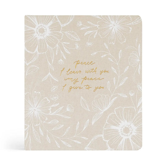 Beige notebook with white floral patterns and gold text on a white background
