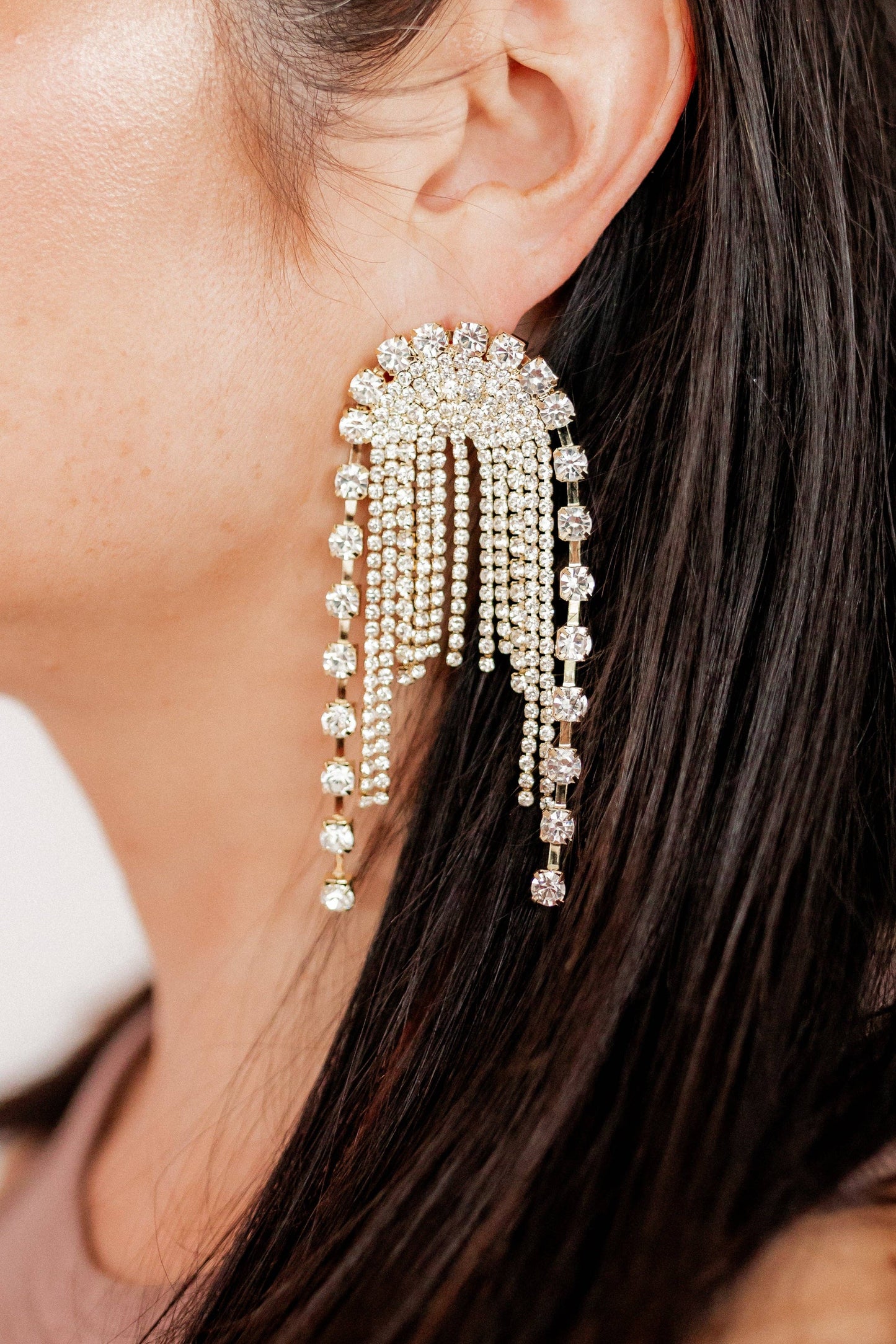 Close-up of a woman wearing a sparkling earring with dangling beads.