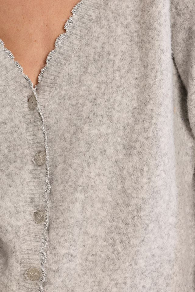 Close-up of a light heather gray knit cardigan with a scalloped edge and front buttons, worn by a model.